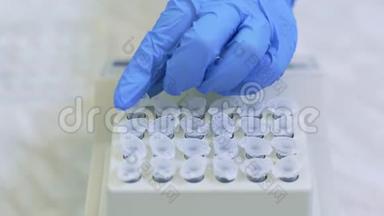 实验室工作人员将样品放入托盘中，对医学实验室中的免<strong>疫病</strong>毒进行分析